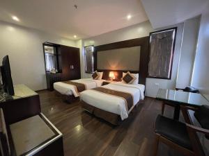 a hotel room with two beds and a television at Moc Tra Hotel Tuan Chau Hạ Long in Ha Long