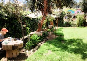 a woman sitting at a table in a garden at Lodge & Camping Suma Samawi in Copacabana