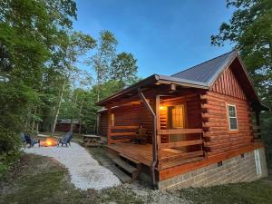 a log cabin with a deck and a table and chairs at Pluggy's Place - Perfect Location - Outdoor Fire pit in Beattyville