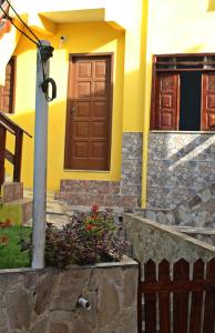 una casa amarilla con una puerta marrón y algunas flores en Casa da Val, en Morro de São Paulo