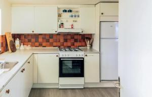 a kitchen with white cabinets and a stove and refrigerator at 1 Bedroom Nice Home In Hurup Thy in Ullerup