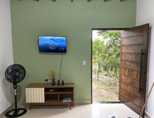 a room with a tv on the wall next to a door at Casa Lilás no Vale do Capão in Vale do Capao
