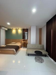 a bedroom with a bed and a couch and a table at Pangeran Residence 2 in Adi Sutjipto