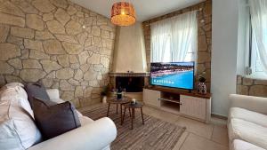 a living room with a white couch and a tv at 7th Heaven Luxury Villa in Kallithea Halkidikis