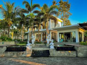 two statues in front of a house with palm trees at The Valerian Villa Ubud in Ubud