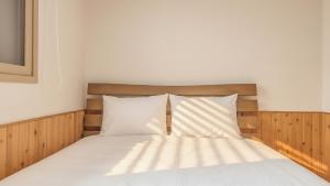 a bed with white sheets and a wooden headboard at suncheon romance pension in Suncheon