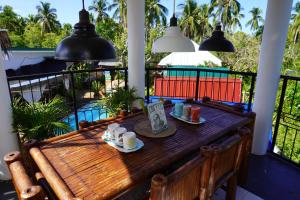 a wooden table on a balcony with cups of coffee at La Provinzia Exclusive Use - 3 Air-Conditioned Rooms 3 Fan Cooled Huts Good for 12 People in Camotes Islands