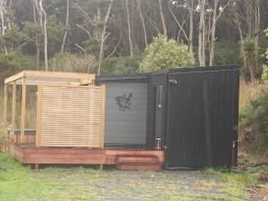 a black and wooden shed with a wooden door at Huruhuru Hideaway! Private Cabin in Otatara +3 photos