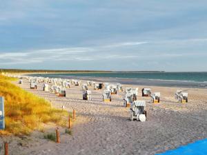 a beach with white chairs and the ocean at Deichblick 02 in Prerow