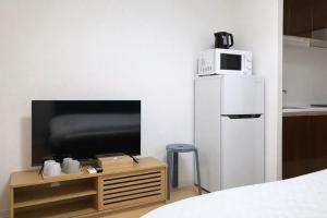 a room with a tv and a refrigerator and a table at 桜の恋 in Osaka