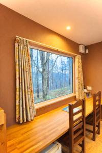 a window in a room with a wooden table and chairs at Auberge Ninguruforet in Biei
