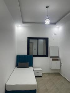 a white room with a bed and a window at Chez montasser in Al Maqārisah