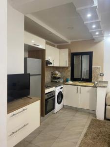 a kitchen with white cabinets and a washer and dryer at Chez montasser in Al Maqārisah +6 photos