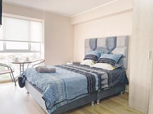 a bedroom with a bed with a blue comforter at Apacible y acogedora habitación con vista a Barranco in Lima