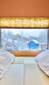 a window with a view of a blue house at Auberge Ninguruforet in Biei