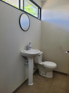 a bathroom with a toilet and a sink and a mirror at Los Senderos in San Juan Opico