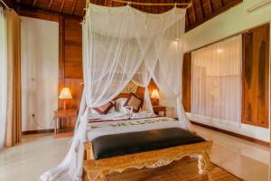 a bedroom with a bed with a canopy at Dukuh Sebatu Villa Ubud in Tampaksiring