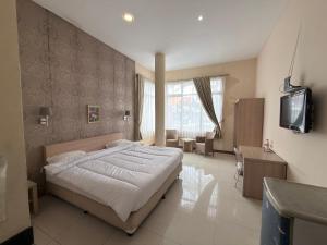 a bedroom with a bed and a tv in it at Guesthouse Anggrek BSD Syariah in Jombang-kulon