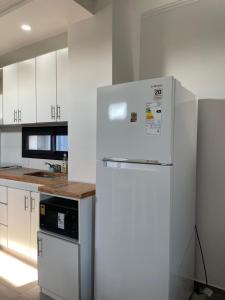 a white kitchen with a white refrigerator in it at YOJU aparthotel in Colón