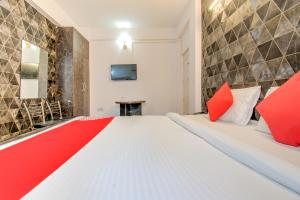 a bedroom with a large white bed with red pillows at Hotel O Kamini in Patna
