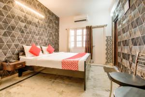 a bedroom with a bed with red pillows and a table at Hotel O Kamini in Patna