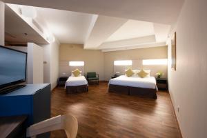 a hotel room with two beds and a flat screen tv at YWCA Fort Canning in Singapore