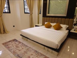 a bedroom with a large white bed with yellow pillows at #MyPawsomeGetaway, Fun Family Retreat, Tanah Rata, Cameron Highlands in Tanah Rata +49 photos