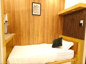 a bedroom with a white bed with a black pillow at #MyPawsomeGetaway, Fun Family Retreat, Tanah Rata, Cameron Highlands in Tanah Rata