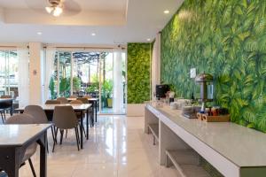 a restaurant with tables and chairs and a green wall at Xanadu Hotel Utapao in Rayong