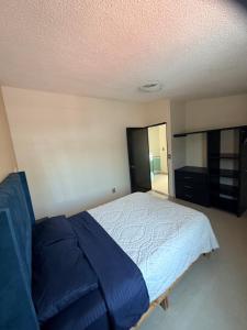 a bedroom with a bed with a blue blanket at Casa de dos pisos,Ciudad Tolteca in Tula de Allende