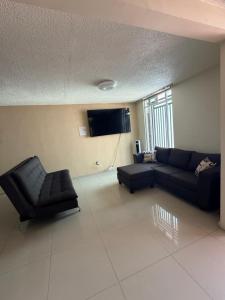 a living room with a couch and a flat screen tv at Casa de dos pisos,Ciudad Tolteca in Tula de Allende
