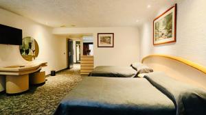 a hotel room with two beds and a desk at Hotel Altum Business in Toluca