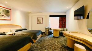 a hotel room with two beds and a couch at Hotel Altum Business in Toluca