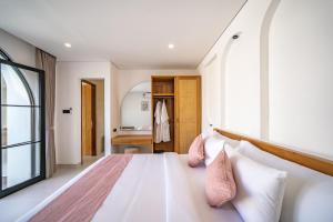 a bedroom with a large white bed with pink pillows at Maui Bingin Villas in Uluwatu