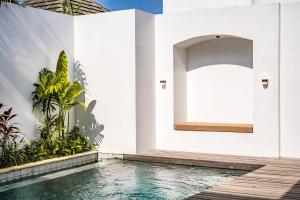 a house with a swimming pool next to a white wall at Maui Bingin Villas in Uluwatu