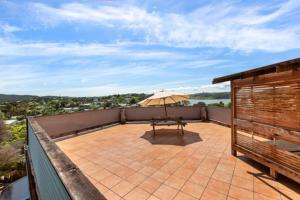 a balcony with a table and an umbrella at Seasidestyle in Raglan