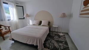 a bedroom with a bed and a chair and a window at Villa Horizon Volcan in Saint-Philippe