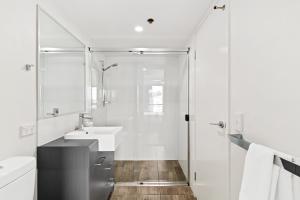 a white bathroom with a shower and a sink at Direct Collective - Pavilion and Governor on Brookes in Brisbane +27 photos
