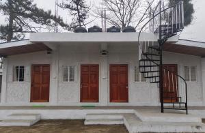 a white house with red doors and a spiral staircase at Peter and Paul Homestay in Shillong
