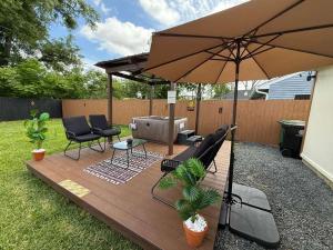 a patio with an umbrella and chairs and a grill at 3BR Houston with Grill, Hot Tub and Game Room near NRG, Downtown and Hobby Airport in Houston