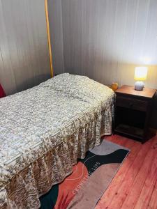 a bedroom with a bed and a table with a lamp at Casa alojamiento Peumallen in Puerto Varas +2 photos