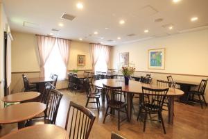 a dining room with tables and chairs and flowers at Hotel Morschein in Matsumoto