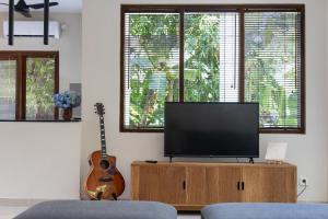 a living room with a television and a guitar at Nami House Balian in Balian