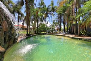 a large pool of water surrounded by palm trees at Bargara Gardens Boutique Villas in Bargara
