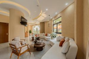 a living room with a white couch and chairs at Mana Hotel Quảng Bình in Dong Hoi