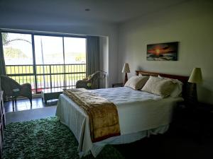 a bedroom with a large bed and a large window at Tutukaka Marina Views in Tutukaka