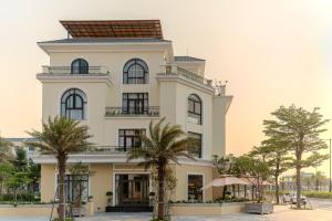 a building with palm trees in front of it at Mana Hotel Quảng Bình in Dong Hoi