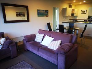 a living room with a purple couch and a kitchen at Tutukaka Marina Views in Tutukaka