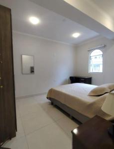 a white bedroom with a bed and a window at La posada apartment in Cusco