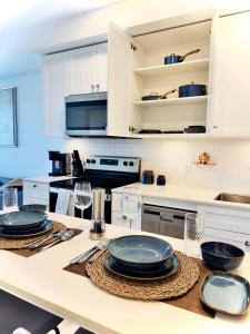 a kitchen with white cabinets and plates on a table at Downtown Condo, Stylish Comfy in Calgary